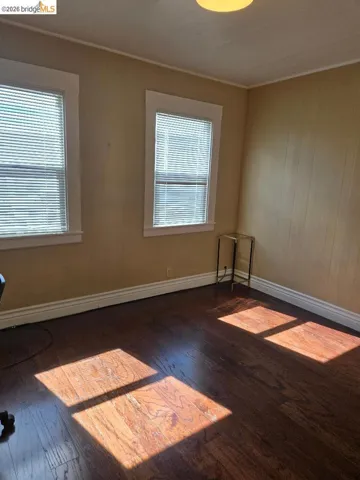 Unfurnished room with dark wood-style flooring and baseboards