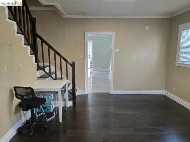 Entrance foyer with crown molding, dark wood-type flooring, and wooden walls