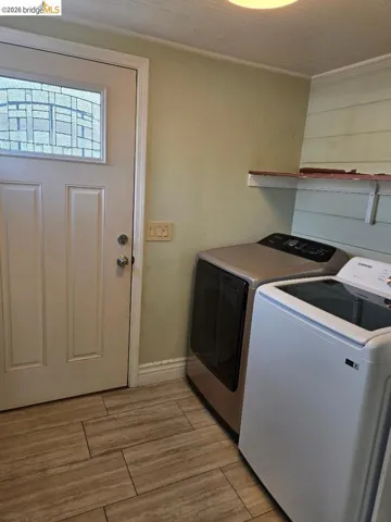 Laundry room with wood finish floors and washing machine and clothes dryer