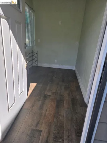 Hallway with dark wood-type flooring and baseboards