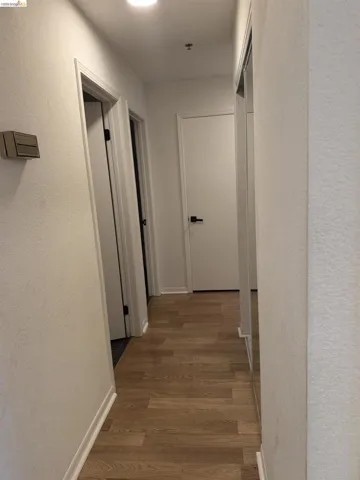 Hall featuring a textured wall and light wood-type flooring