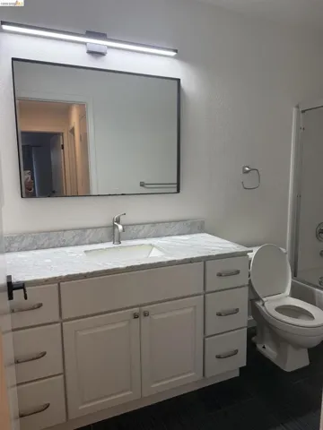Full bathroom with vanity, shower / tub combination, and a textured wall