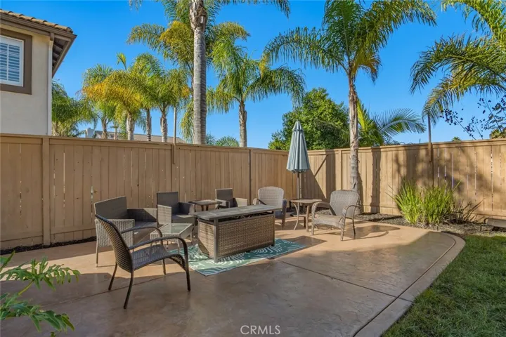 Step outside to a backyard designed for both relaxation and ease, with extended concrete patio space, swaying palm trees, and a low-maintenance layout.