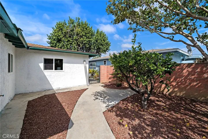 The large wrap-around backyard is a private blank canvas ready for your imagination, featuring block wall fencing, multiple fruit trees including avocado, and two large storage sheds, offering endless possibilities for entertaining, gardening, or a future ADU.