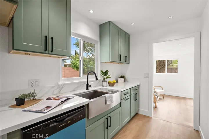 The light and bright living room flows seamlessly into the completely redesigned kitchen boasting quartz countertops, custom self-closing cabinetry, stainless steel appliances, a farmhouse sink, and an eat-in dining area.