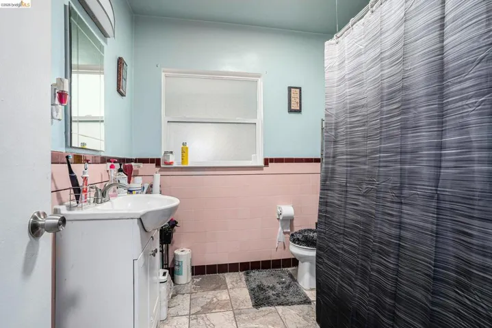 Bathroom with vanity, tile walls, a shower with shower curtain, and a wainscoted wall