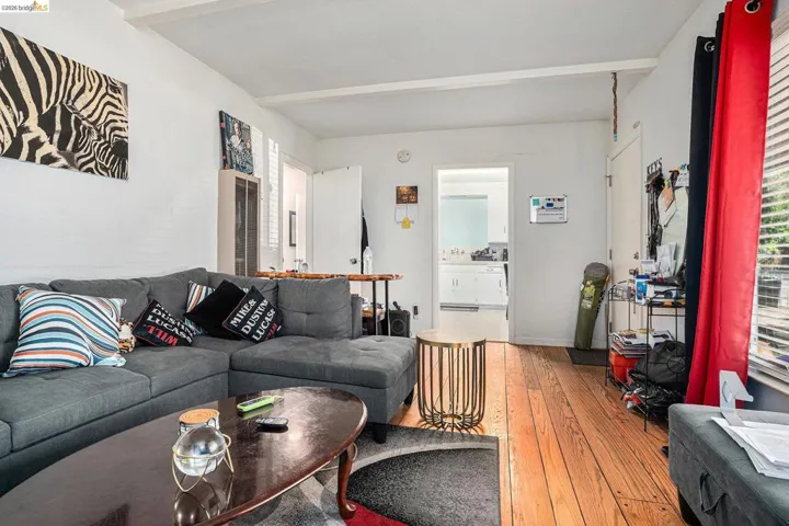 Living room with light wood-style floors and beam ceiling