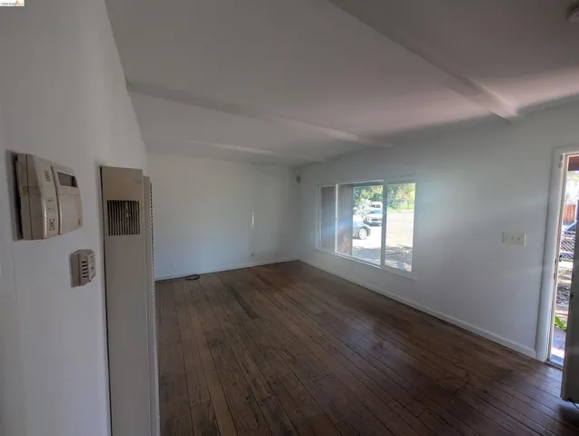Spare room with dark wood-style flooring, a heating unit, and beam ceiling