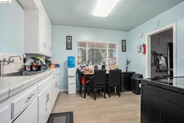 Kitchen featuring tile counters, white cabinets, and black range with electric cooktop