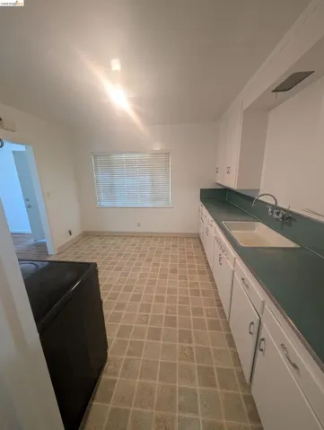Kitchen with white cabinets, black range with electric cooktop, and dark countertops
