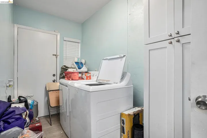 Laundry area featuring independent washer and dryer, wood finished floors, and cabinet space