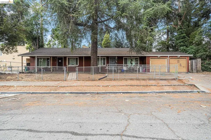 Single story home with roof with shingles, an attached garage, a fenced front yard, and a gate