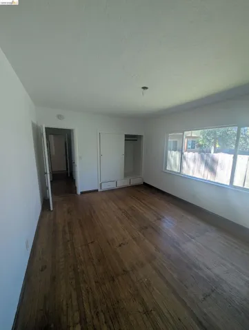 Unfurnished bedroom with dark wood-style floors and a closet