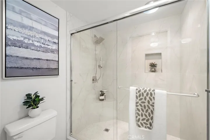 the hall bath offers a tub/shower combination while the primary features an expanded walk-in shower with sitting bench and multiple shower fixtures.