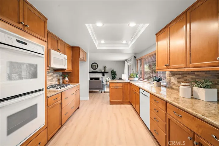The remodeled kitchen features granite countertops, a mosaic glass tile backsplash, custom self-closing cabinetry w/pull-outs