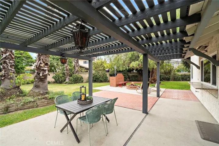 park-like wrap-around backyard that is filled with beauty and tranquility with lush lawn, tropical landscaping, a covered patio with paver-accented decking