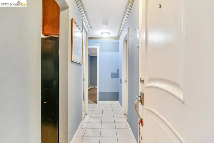 Hallway featuring light tile patterned flooring and crown molding