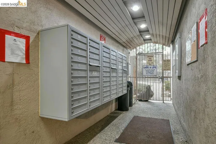 View of community featuring mail area, vaulted ceiling, a textured wall, and recessed lighting