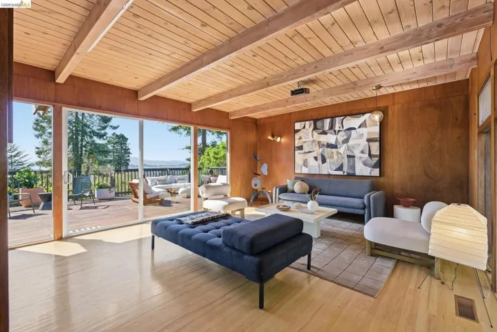 Living room with wood finished floors, wood walls, and a wood ceiling with exposed beams