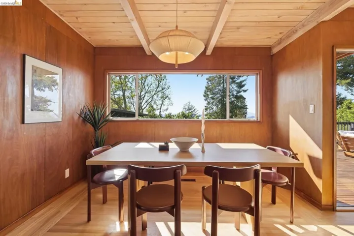 Dining space featuring wood finished floors, healthy amount of natural light, a wooden ceiling with exposed beams, and wood walls