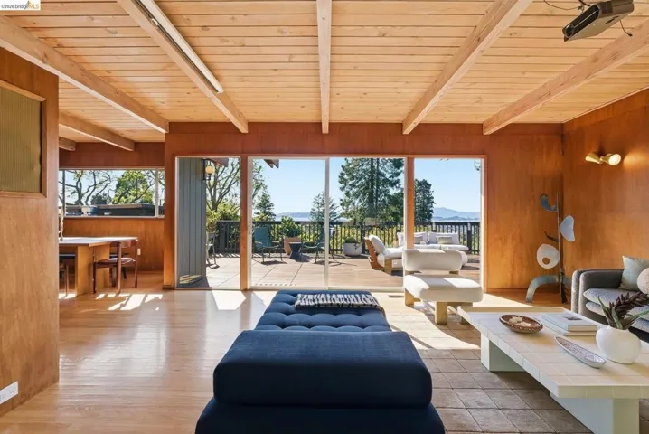 Living room with wood walls, a wood ceiling with exposed beams, and wood finished floors