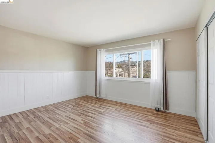 Unfurnished room with light wood finished floors and wainscoting