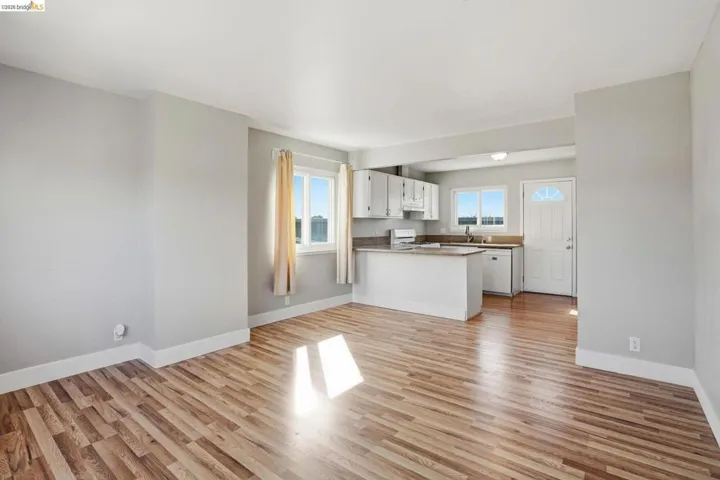Unfurnished living room featuring light wood-style flooring and baseboards