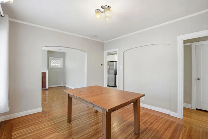 Unfurnished dining area with light wood finished floors, ornamental molding, and arched walkways