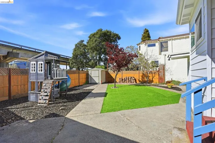 Fenced backyard featuring a storage unit