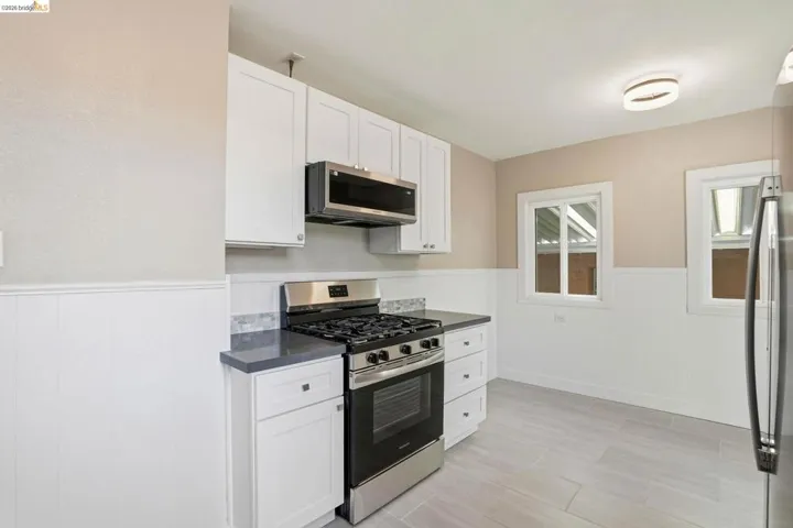 Kitchen featuring a wainscoted wall, stainless steel appliances, and white cabinets