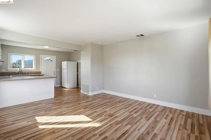 Unfurnished living room featuring light wood-style floors and baseboards