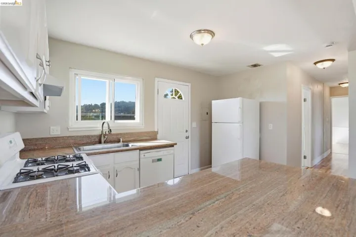 Kitchen featuring white appliances, white cabinetry, and a peninsula