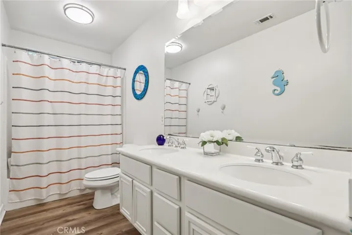 Upstairs bathroom with dual-sink vanity and shower/tub combination designed for family or guest use