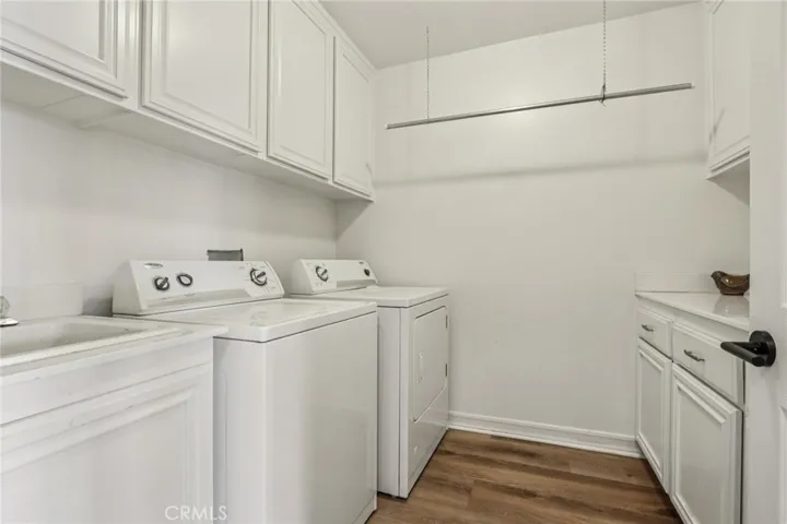 Main-level laundry room featuring generous cabinet storage, utility sink, and counter space for everyday use