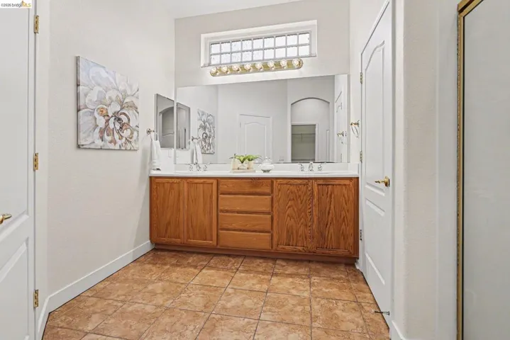 Full bathroom with double vanity and baseboards