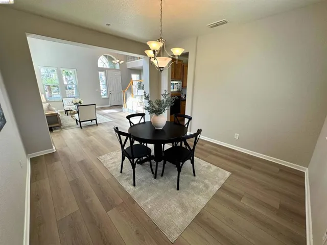 Dining area with a chandelier, light wood-style floors, and a textured ceiling