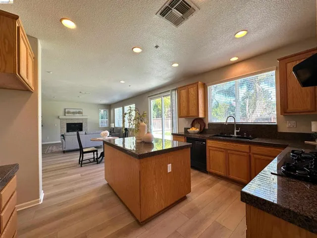 Kitchen featuring a center island, recessed lighting, a fireplace, light wood-style flooring, and black appliances