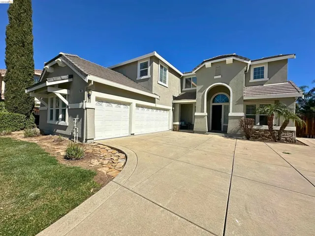 View of front of home with a tile roof, stucco siding, concrete driveway, and an attached garage