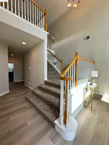 Stairs featuring wood finished floors and a high ceiling