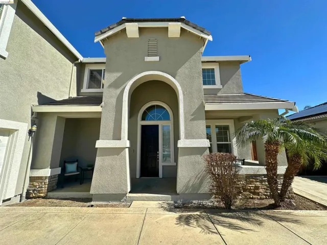 View of exterior entry with a porch, stucco siding, stone siding, and a tile roof
