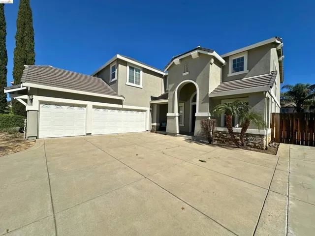 View of front of property with a tile roof, concrete driveway, stucco siding, and an attached garage