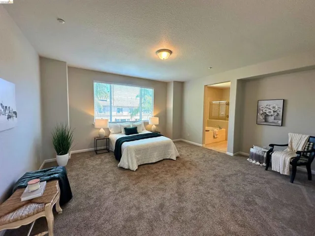 Carpeted bedroom featuring connected bathroom and a textured ceiling
