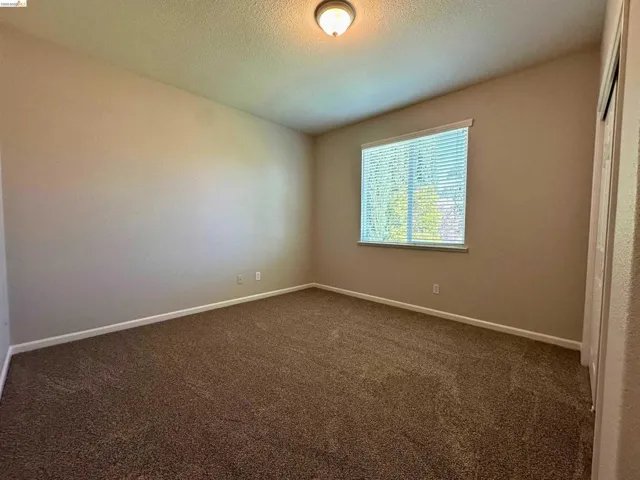 Empty room with dark colored carpet and a textured ceiling