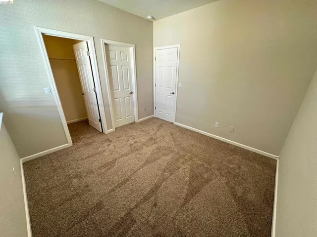 Unfurnished bedroom with a walk in closet, a textured wall, and carpet flooring