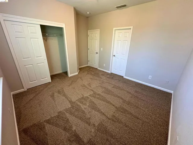 Unfurnished bedroom featuring a closet and dark carpet