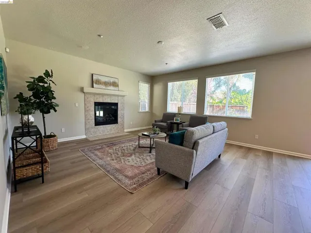 Living room featuring a fireplace, light wood-style flooring, and a textured ceiling