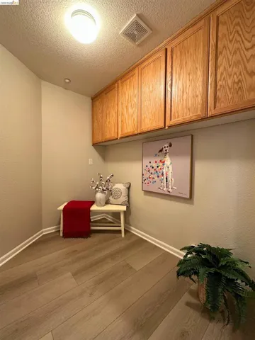 Living area featuring light wood-style flooring, a textured wall, and a textured ceiling