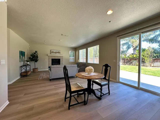Dining room featuring light wood-type flooring, a fireplace, a textured ceiling, and recessed lighting