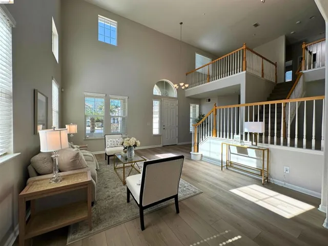 Living area with wood finished floors, hanging lights, and a high ceiling