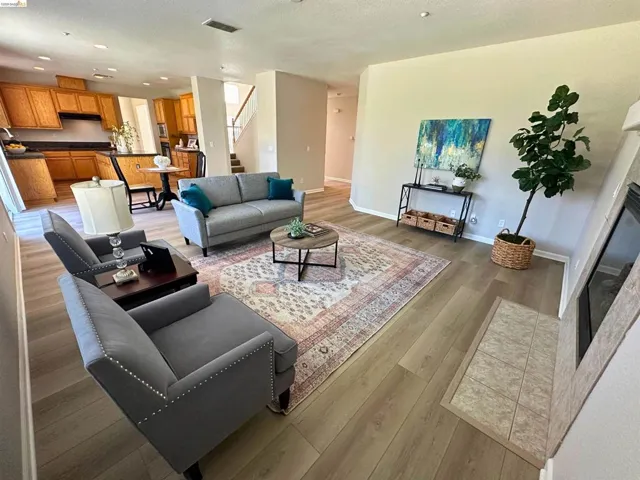 Living room featuring light wood-type flooring, a tiled fireplace, recessed lighting, and a textured ceiling